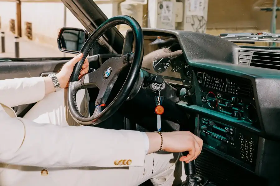 Driver shifting gear in a classic BMW 635CSi during a vintage car experience in Romania
